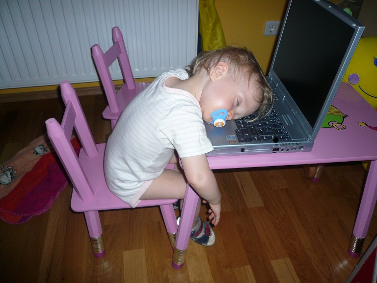 kleines Mädchen, mit dem Kopf auf dem Notebook liegend eingeschlafen